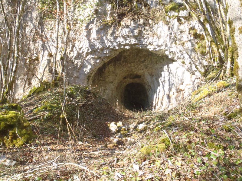 Entrée de la cavité la plus à l'E.
Le talus d'éboulis de part et d'autre du porche atteste de l'existence de travaux dans chacune des 3 petites grottes. Le calcaire de la couche karstifiée est ici assez dolomitisée. La présence de blocs émoussés de roches dures (voir autre photo), dans l'éboulis du 1° plan, paraît attester de l'existence d'un équipement de broyage de minerai, aujourd'hui retiré des lieux, à l'excpetion des galets de broyage.
Fichier manquant